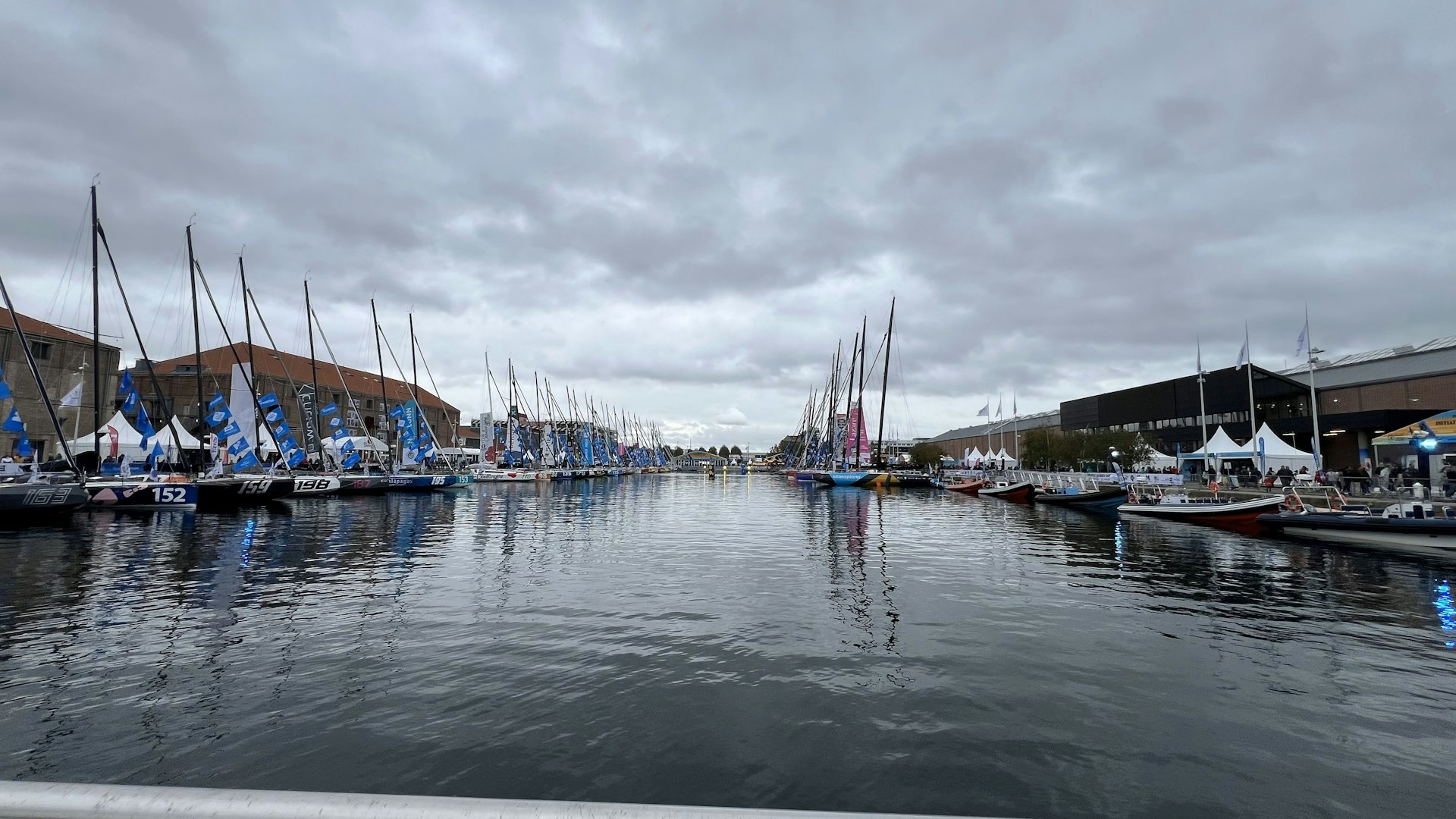 a harbor filled with lots of sailboats under a cloudy sky